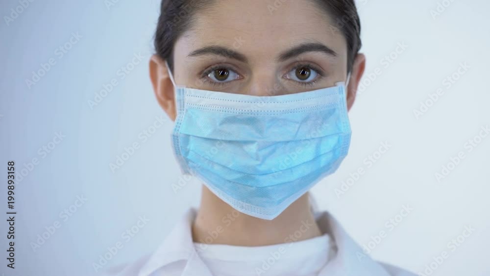 Young female doctor wearing surgical mask, safety while examining, closeup Young female doctor wearing surgical mask, safety while examining, closeup