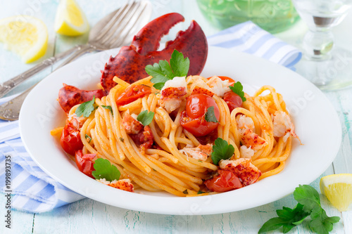 Spaghetti with lobster and cherry tomatoes served on white plate