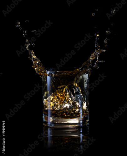 Splash of ice in a glass of whiskey
