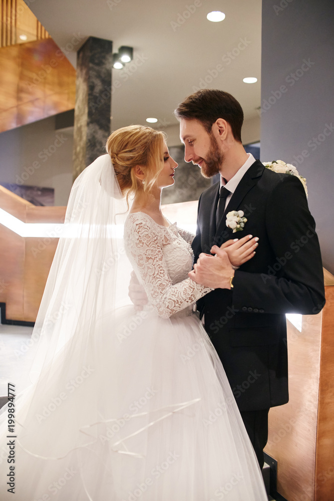 Naklejka premium Wedding couple hugging and kissing, the first day of life together. Bride and groom after wedding ceremony, beautiful couple loves each other and hugging