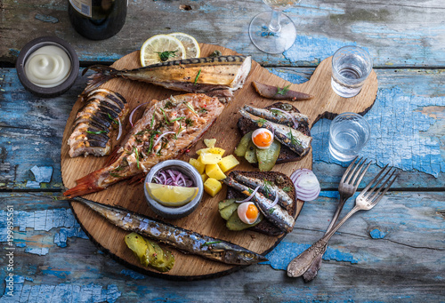 Smoked fish appetizers with mackerel, sturgeon, perch on woden cutting board