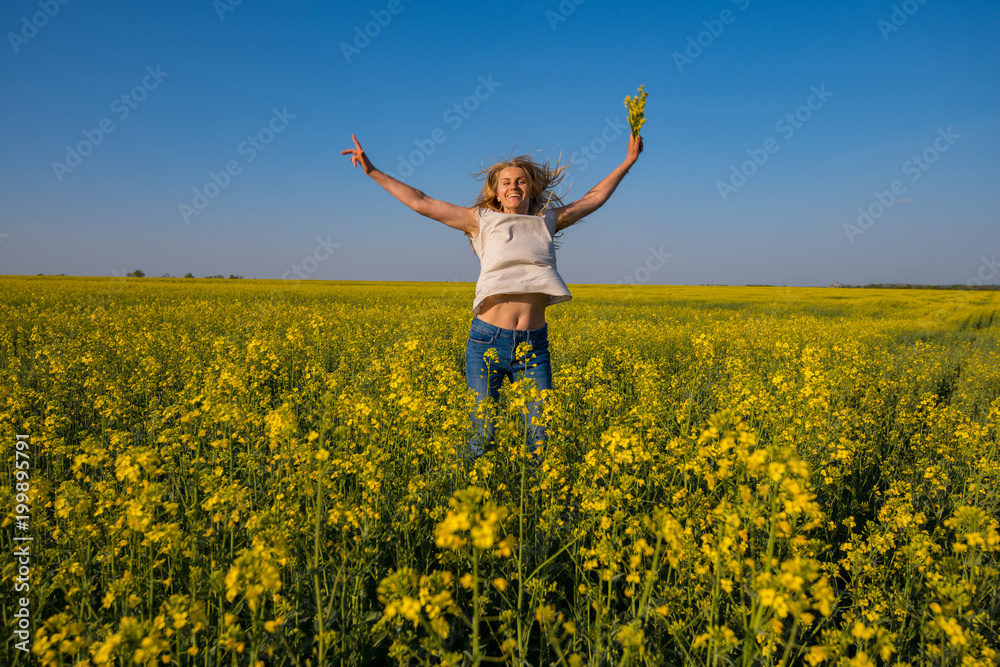 Joyful beautiful woman blonde, with open arms, jumps on the field Joyful beautiful woman blonde, with open arms, jumps on the field