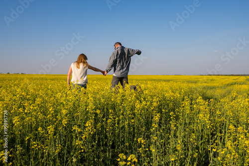 Joyful couple, with open arms, is jumping on the field © sanechka