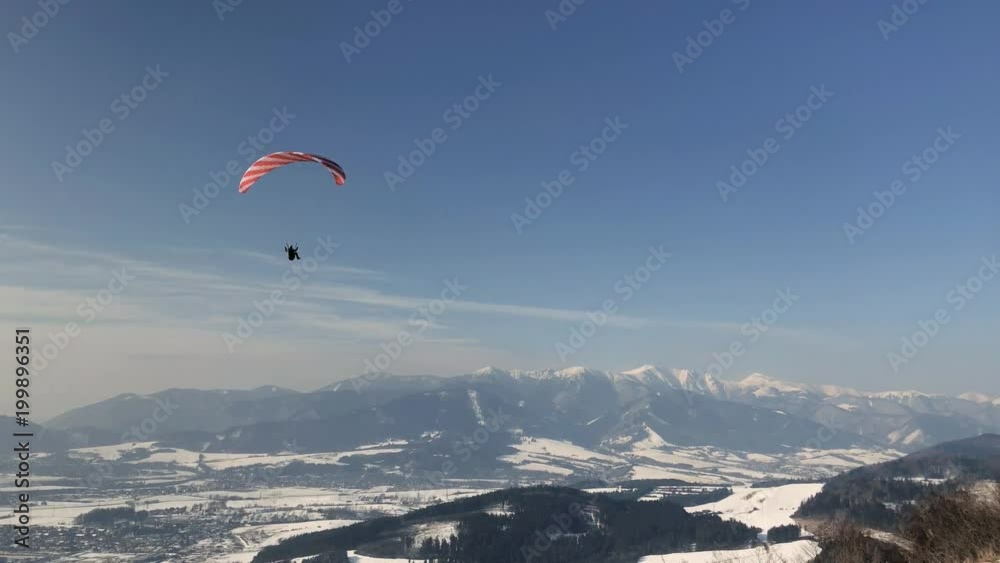 Paraglider flies in the sky on a sunny winter day Paraglider flies in the sky on a sunny winter day