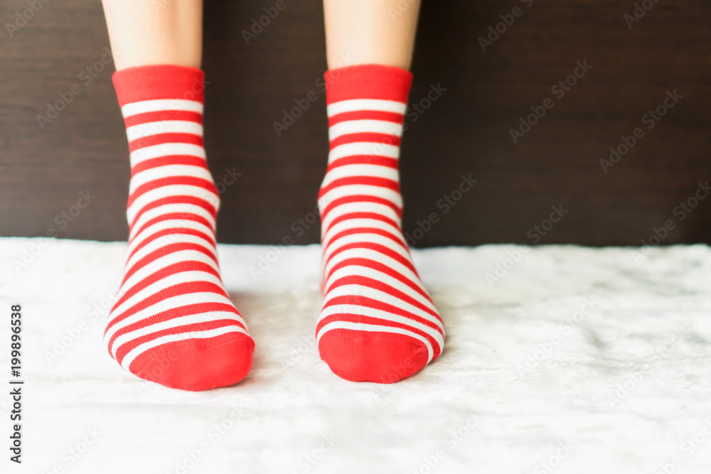Legs in socks red colors alternate, white side stand on white fabric floor. Legs in socks red colors alternate, white side stand on white fabric floor.