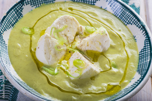 Crema o sopa de calabacín con manzana y cebolleta y queso mozzarella aderezada con aceite de oliva virgen extra para una dieta vegetariana y saludable photo