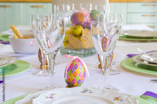 Shot of a set table for a family eastern lunch/dinner. With a colourful egg/eggs, dishes with flowers and wine glasses
