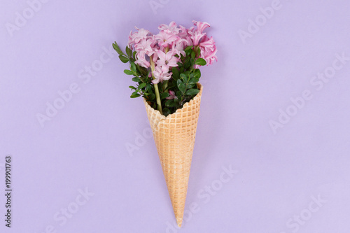 Top view of waffle cone with flowers bouquet on lilac or violet background, flat lay © uv_group