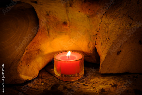 Prayer and hope concept. Retro pink candle light in crystal glass and old wooden photo