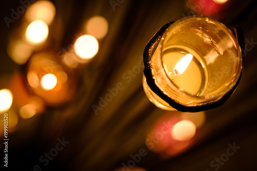 Prayer and hope concept. Retro pink candle light in crystal glass and old wooden