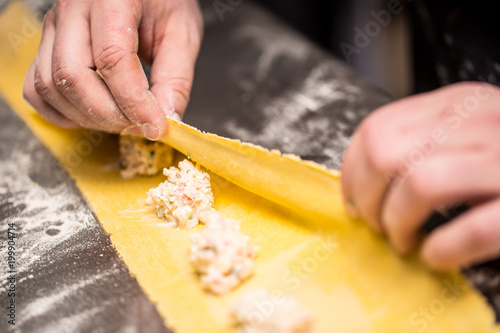 Chef's hands prepares Italian food stuffed pasta ravioli