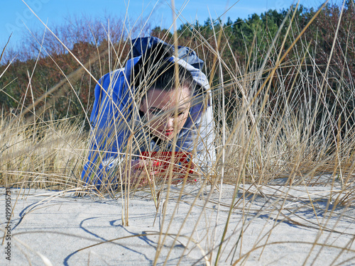 Kobieta robiąca zdjęcie ukryta za wydmą