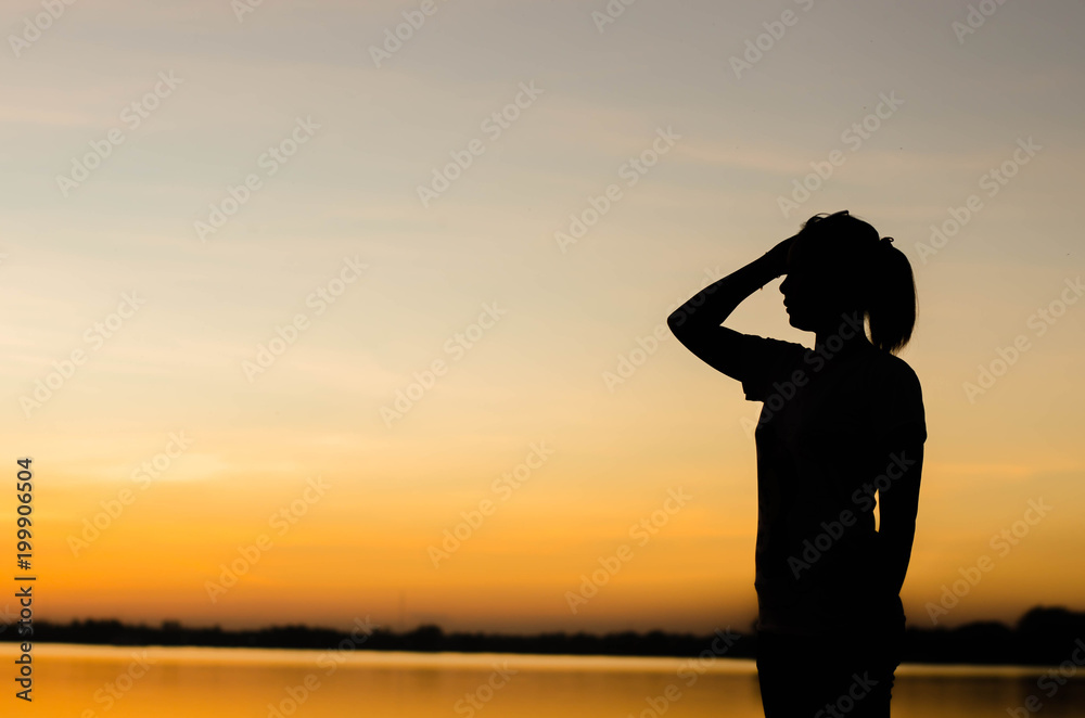 Fototapeta premium The silhouette of a woman standing looking forward with hope.