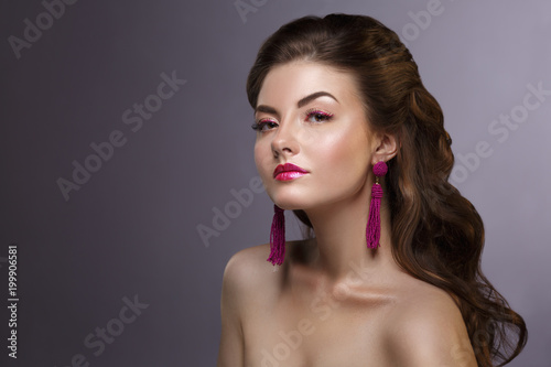 Fashion beauty portrait of a beautiful girl with a bright make-up and an elegant hairstyle on a gray background.