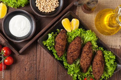 Traditional arabic kibbeh with lamb and pine nuts. Top view. Natural wooden background.