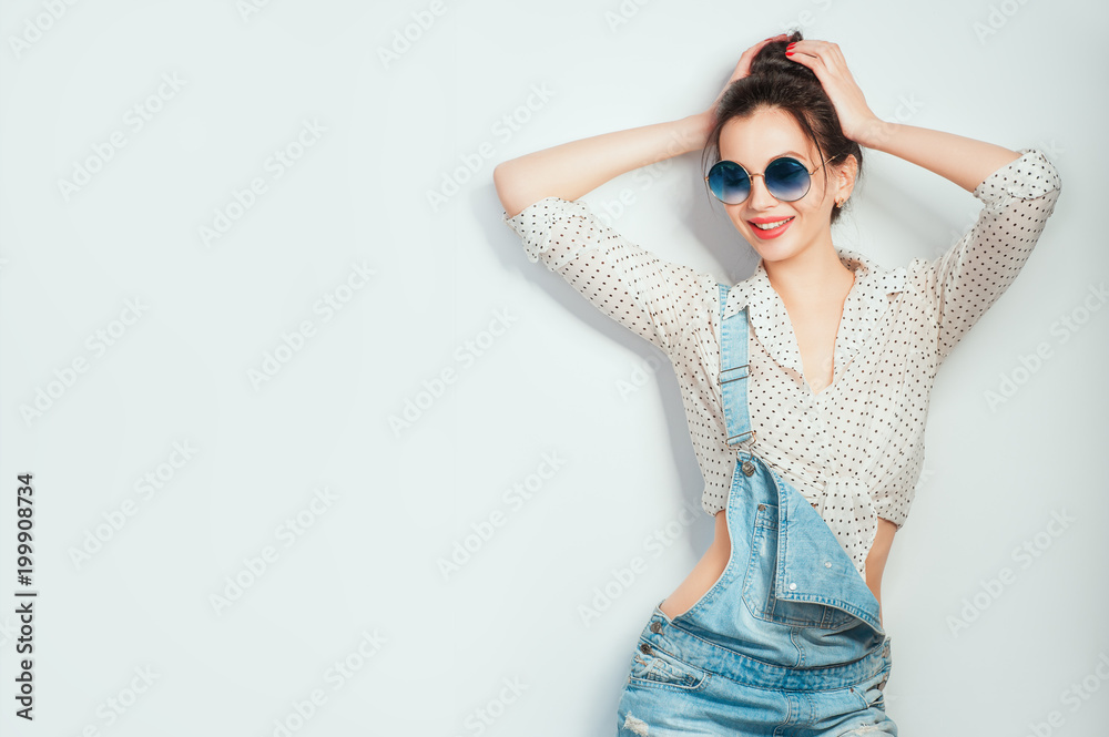 Lets dance! Young beautiful cheerful woman with hair bun in sunglasses wearing in jeans shorts dancing and posing over white wall. Good mood. People Emotions Beauty Fashion Lifestyle concepts Lets dance! Young beautiful cheerful woman with hair bun in sunglasses wearing in jeans shorts dancing and posing over white wall. Good mood. People Emotions Beauty Fashion Lifestyle concepts