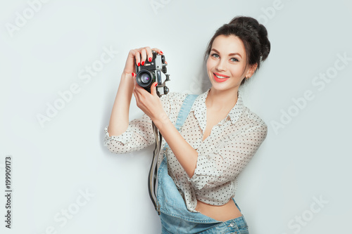 Fashion look, pretty cool young woman model with retro camera wearing in denim clothes posing on white wall. Expressive beauty girl photographer holding photocam. Emotions Lifestyle People concepts photo