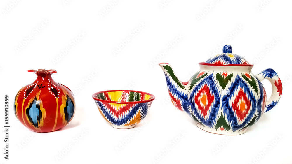 traditional ceramic Uzbek utensils - kettle, bowl, plate with ornament Ikat on white background Flat lay