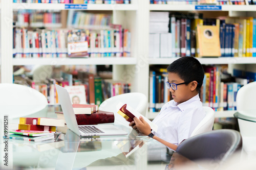 Asian student is searching for knowledge with laptop in the library.