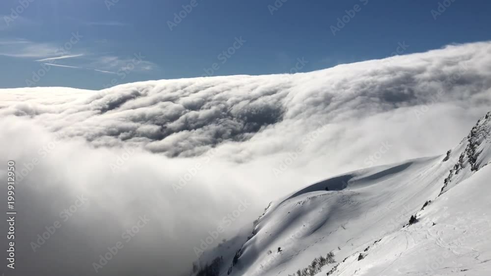 Beautiful winter panorama of a snowy mountains, and very low huge and fast moving clouds