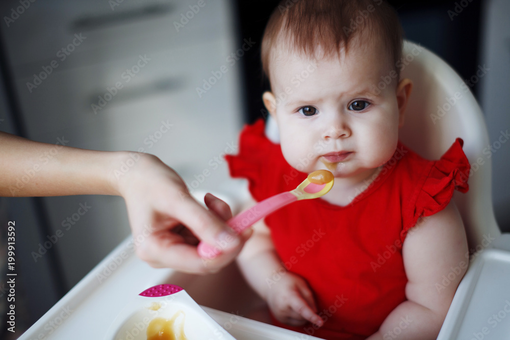 baby in a red dress is sitting on a child's chair baby in a red dress is sitting on a child's chair