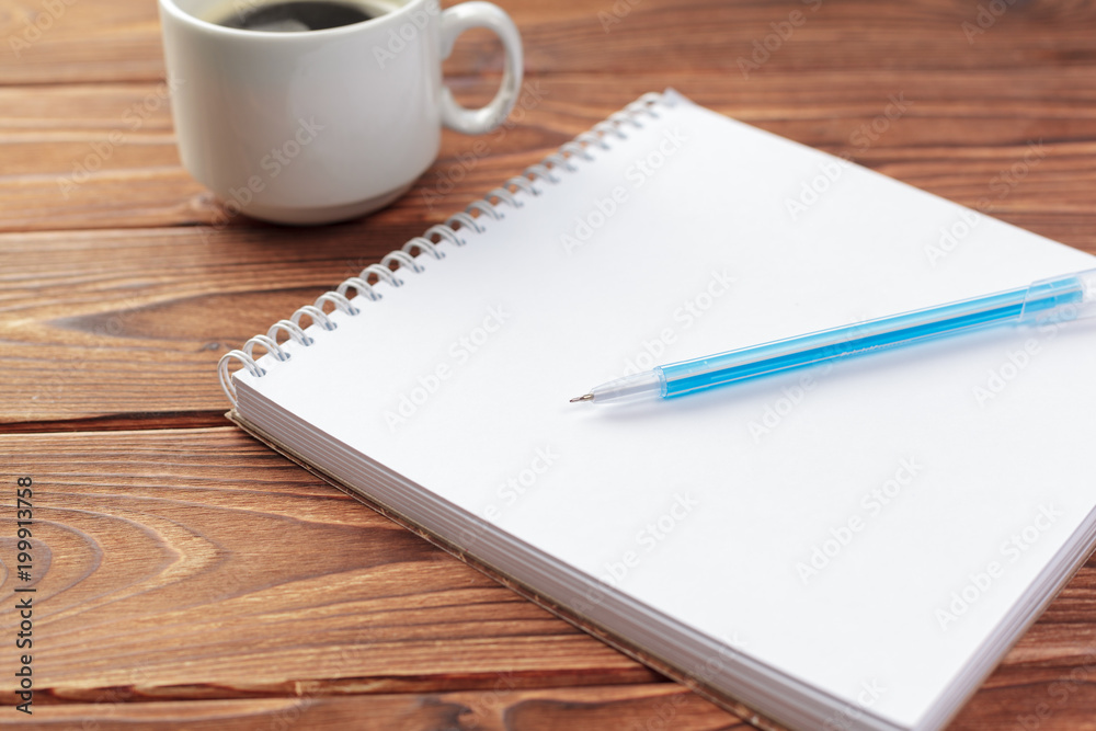 Office desk table top view. Notepad with blank pages on wooden table Office desk table top view. Notepad with blank pages on wooden table