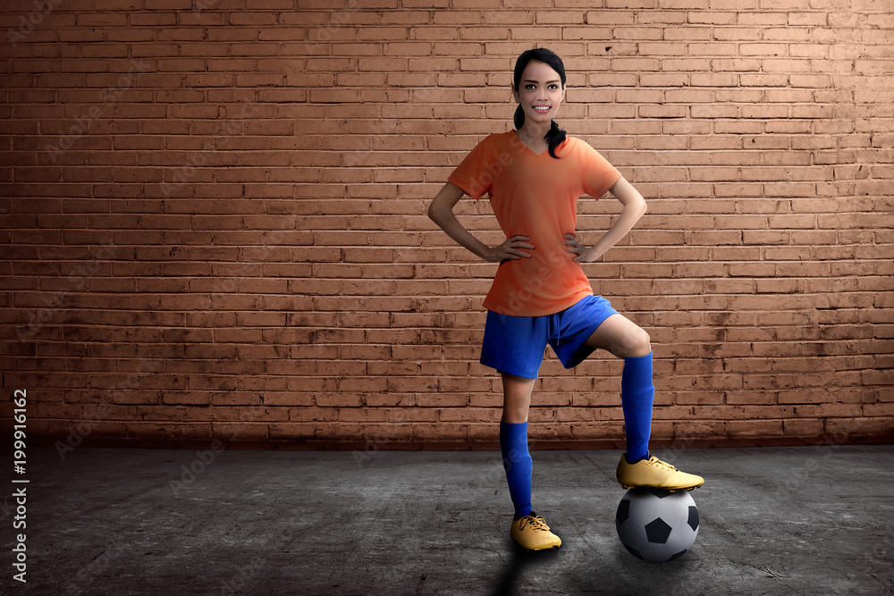 Beautiful asian female footballer standing with ball on her feet Beautiful asian female footballer standing with ball on her feet
