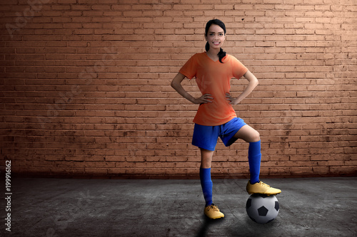 Beautiful asian female footballer standing with ball on her feet