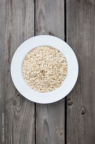 Oatmeal  rolled oats on a plate with glass of milk on white wooden table. 