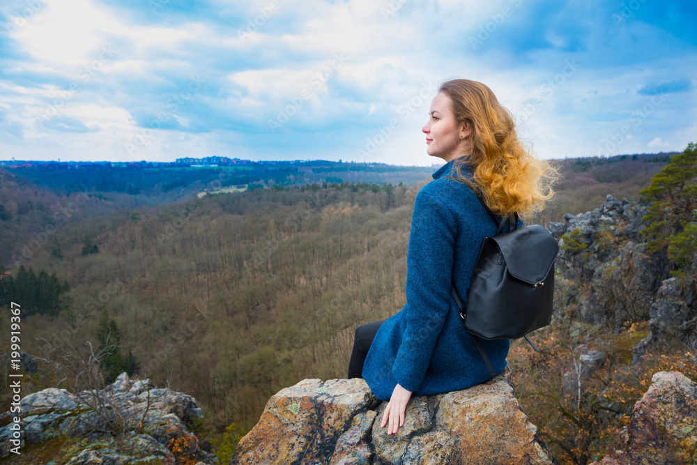 The girl sitting on the rock in mountain, relaxing in nature The girl sitting on the rock in mountain, relaxing in nature