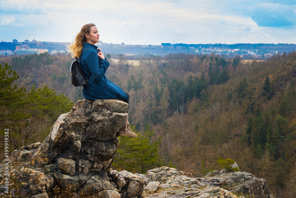 The girl sitting on the rock in mountain, relaxing in nature