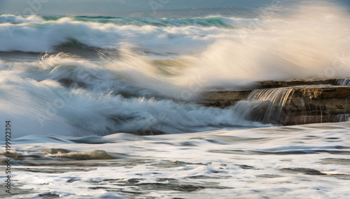 Rocky seashore with wavy ocean and wind waves crashing on the rocks