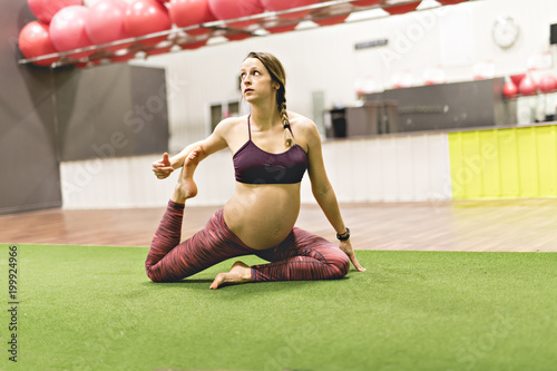 Fototapeta Pregnant woman is doing exercises at the gym