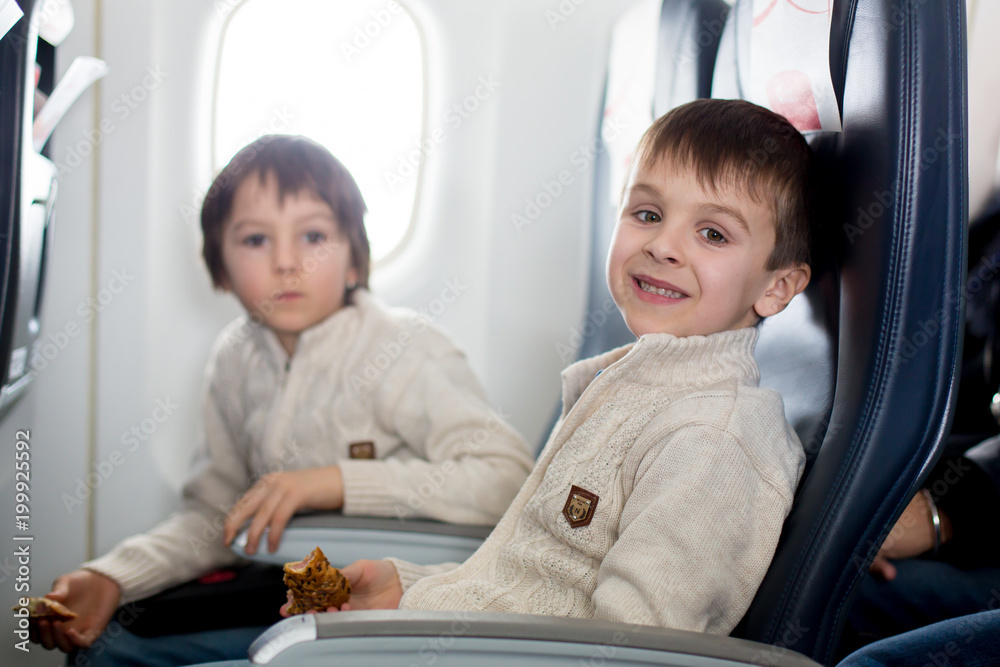 Two children, eating sandwiches on board in aricraft, traveling on vacation Two children, eating sandwiches on board in aricraft, traveling on vacation
