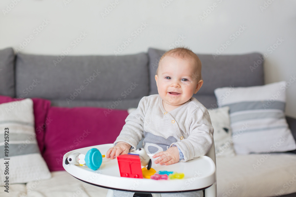 Cute baby boy, playing with toys at home, sitting in high chair Cute baby boy, playing with toys at home, sitting in high chair