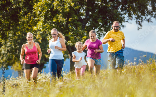 Family, mother, father and kids running for sport over a meadow