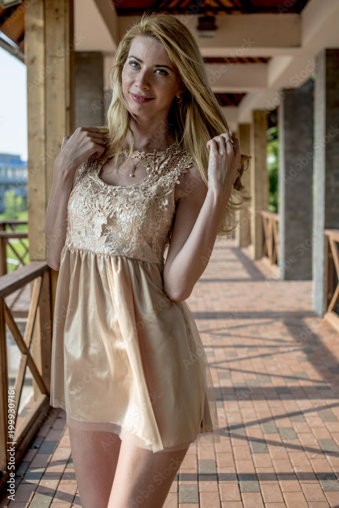 Young beautiful blonde woman in a beautiful dress on a Russian wooden staircase
