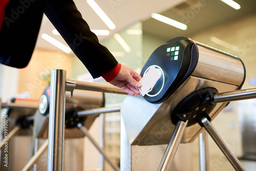 Close up of unrecognizable businesswoman swiping card passing turnstile to enter building photo