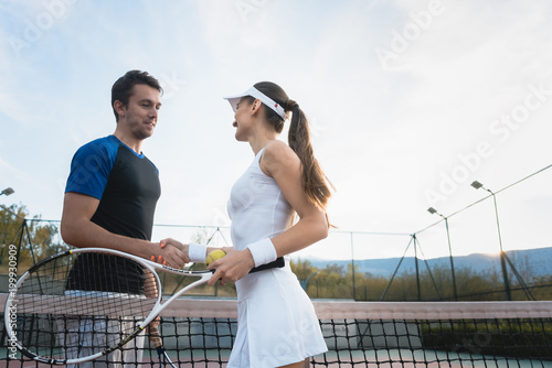 Man and woman shaking hands at net after match of tennis © Kzenon