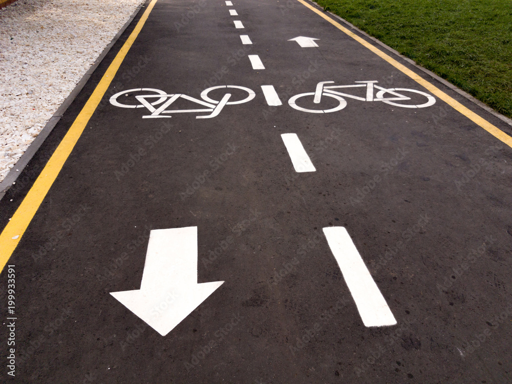 White bicycle sign with arrow on the asphalt, bike road sign on the street, bicycle lane sign on street, gray background White bicycle sign with arrow on the asphalt, bike road sign on the street, bicycle lane sign on street, gray background