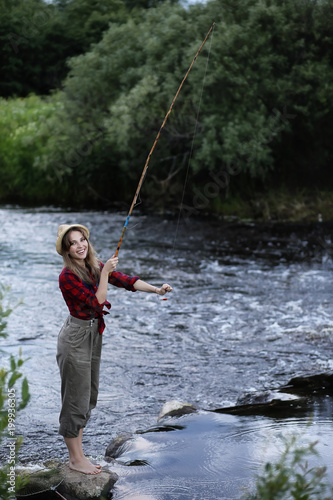 Girl by the river with a fishing rod