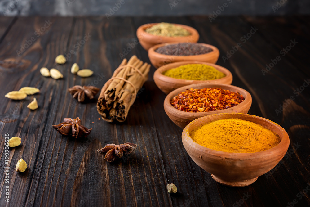  colorful spices in ceramic bowls on wooden table