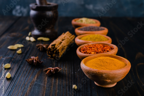  colorful spices in ceramic bowls on wooden table