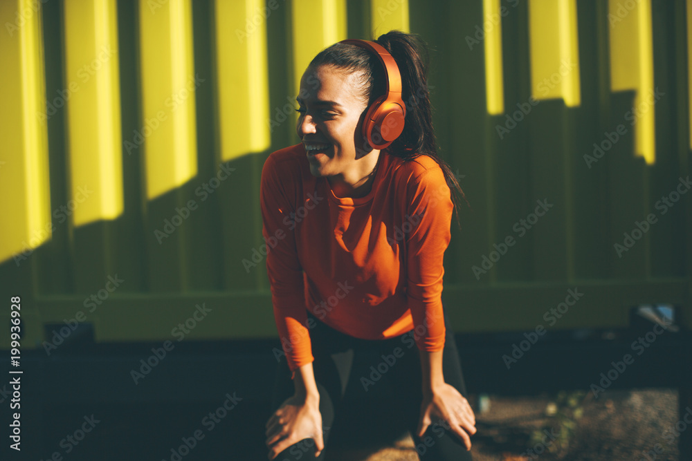 Fototapeta premium Young attractive female runner taking break after jogging outdoors