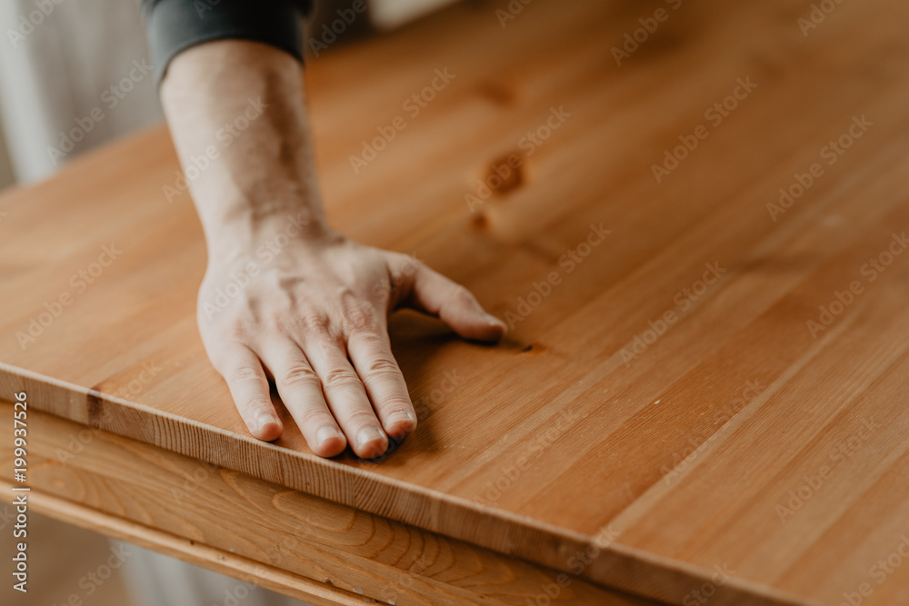 man passes his hand over the finished wooden table man passes his hand over the finished wooden table