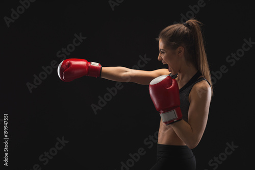Side view of emotional young woman with boxing gloves