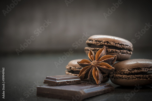 chocolate or coffee taste french macaroons on dark background, selective focus, crushed chocolate and badiyan anise flower