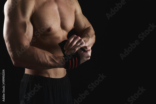 Athletic boxer wrapping hands with boxing bandage
