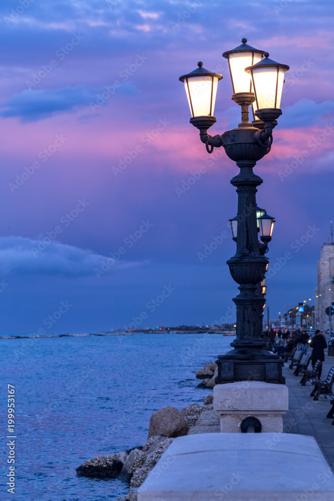 Ancient street lamp on seafront at sunset. Bari, Italy coastline