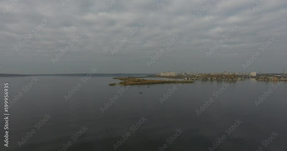 Aerial view from above of the bay with fishermen on a boat and on a sandy scythe and city on the horizon Top view of a boat with a fisherman who catches fish for fishing rod Aerial view from above of the bay with fishermen on a boat and on a sandy scythe and city on the horizon Top view of a boat with a fisherman who catches fish for fishing rod
